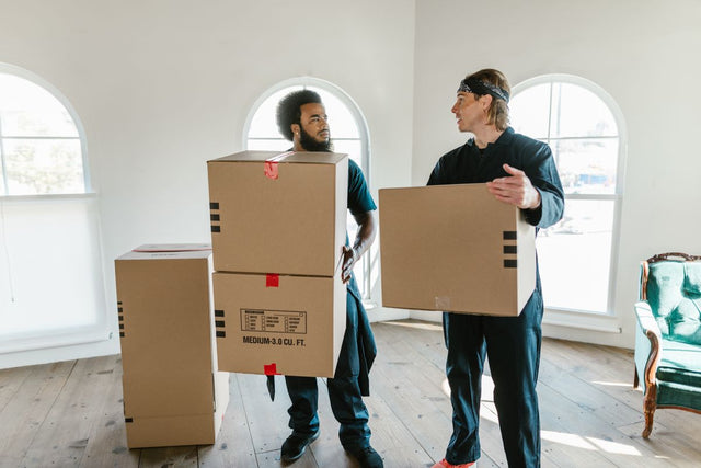 Professional movers carrying boxes in an office space