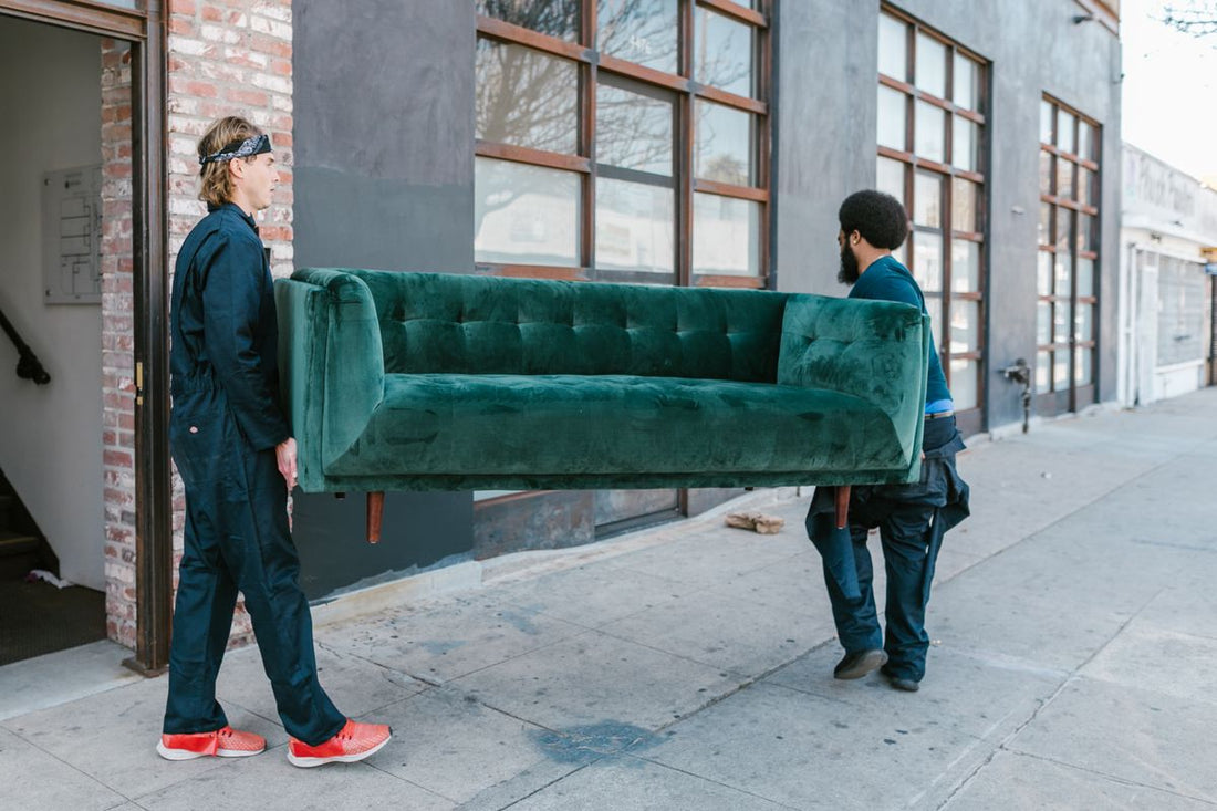 Two movers carrying a sofa on a city street