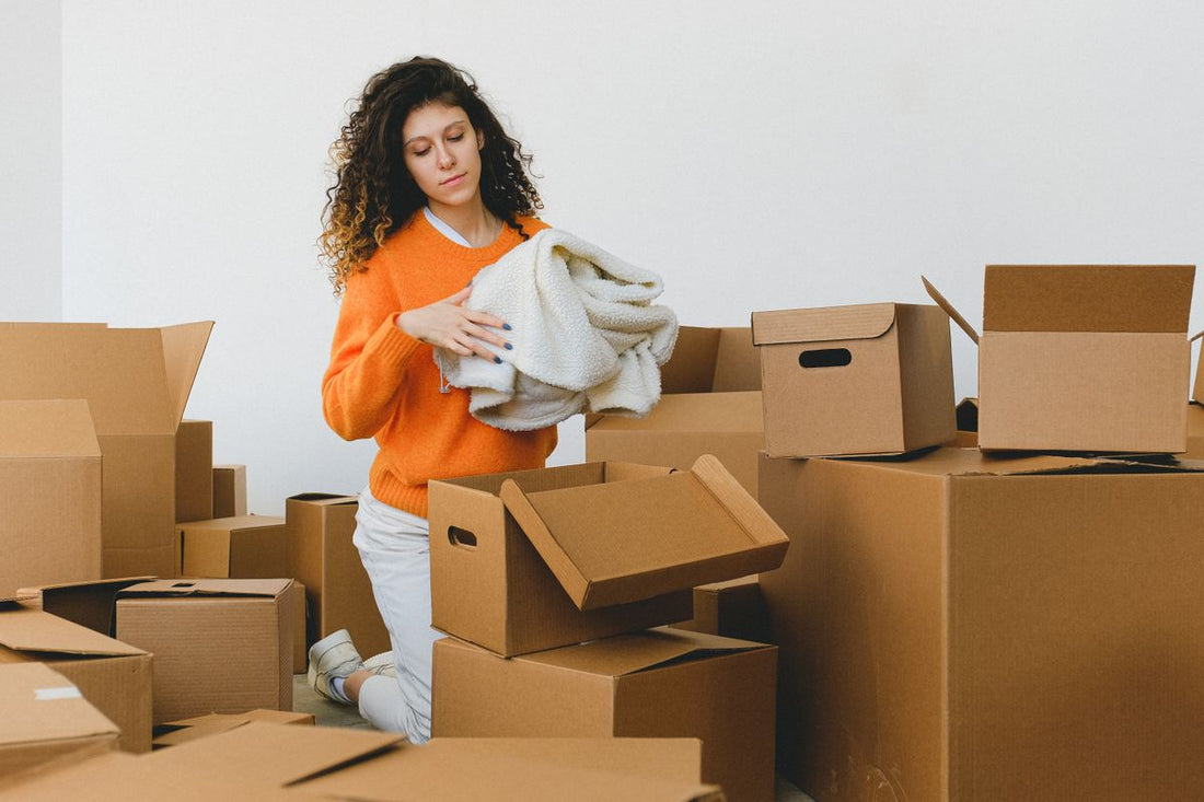 Person carefully packing belongings into boxes