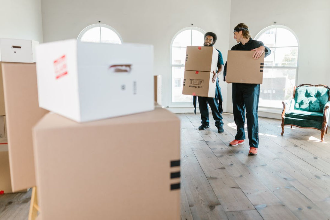 Uniformed movers carrying boxes into a new home